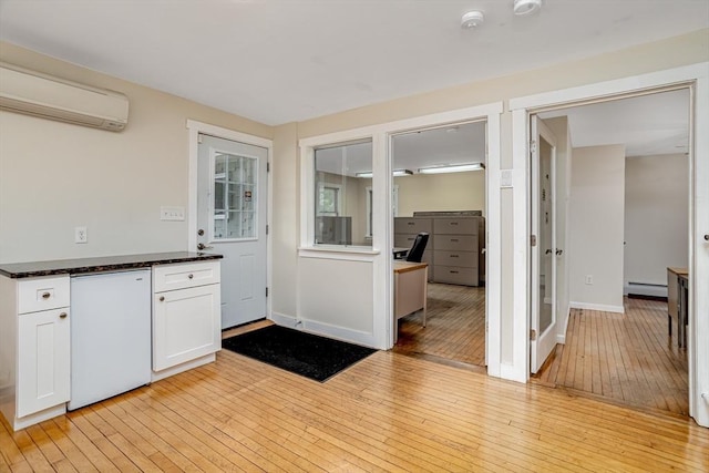 18 Main St, Templeton, MA 01468 - kitchen with a wall mounted air conditioner, a baseboard heating unit, light wood-style floors, white cabinets, and dark stone countertops