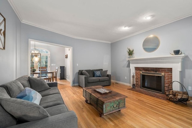 living area with crown molding, a fireplace, light wood-type flooring, and baseboards