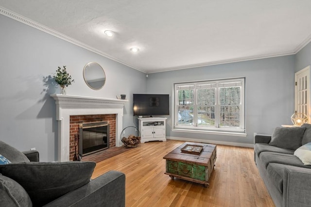 living area with crown molding, light wood-style flooring, a fireplace, and baseboards