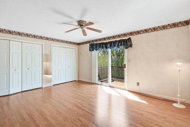 unfurnished bedroom with access to exterior, two closets, wood finished floors, and baseboards