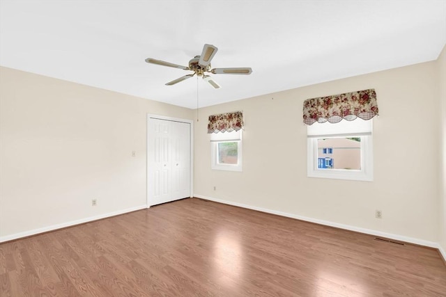 empty room with wood finished floors, baseboards, and a ceiling fan