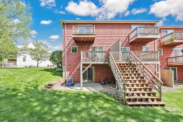 rear view of house featuring a yard, a patio area, and stairs