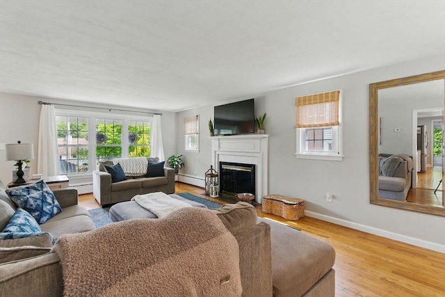 905 Stony Hill Rd, Wilbraham, MA 01095 - living room with wood finished floors, a glass covered fireplace, a baseboard radiator, and baseboards