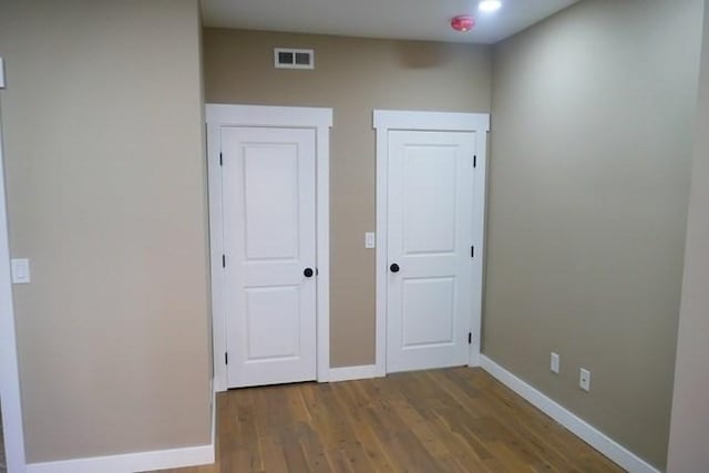 unfurnished bedroom with visible vents, baseboards, and wood finished floors