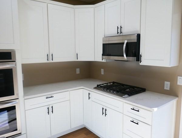 kitchen with stainless steel appliances, white cabinets, light countertops, and wood finished floors