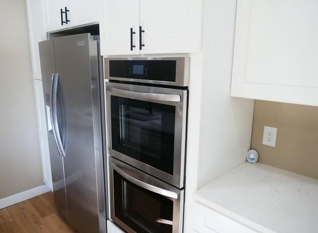 kitchen with light stone countertops, white cabinetry, and appliances with stainless steel finishes