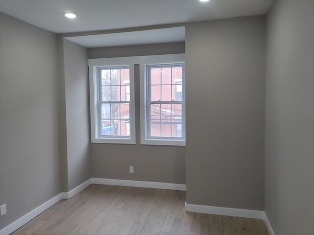 empty room featuring recessed lighting, baseboards, and light wood finished floors