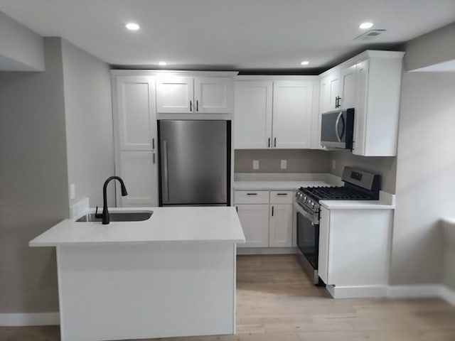 kitchen with stainless steel appliances, light countertops, white cabinetry, and a sink