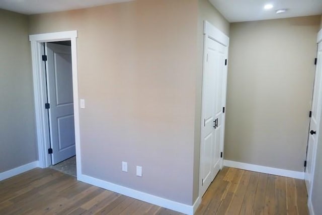 hallway featuring wood finished floors and baseboards