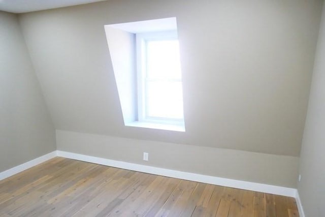 additional living space with lofted ceiling, wood-type flooring, and baseboards