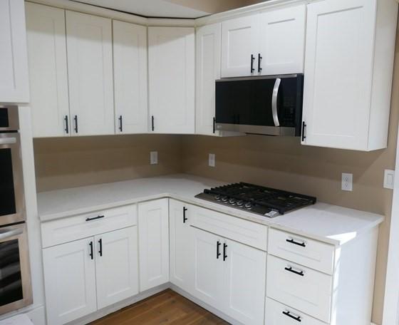 kitchen with white cabinetry, stainless steel appliances, light countertops, and wood finished floors