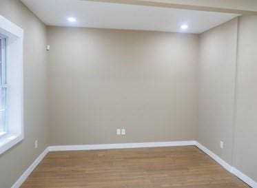 empty room with baseboards, wood finished floors, and recessed lighting