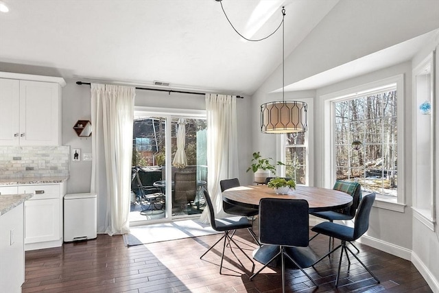 dining area with a wealth of natural light, lofted ceiling, and dark wood-style flooring