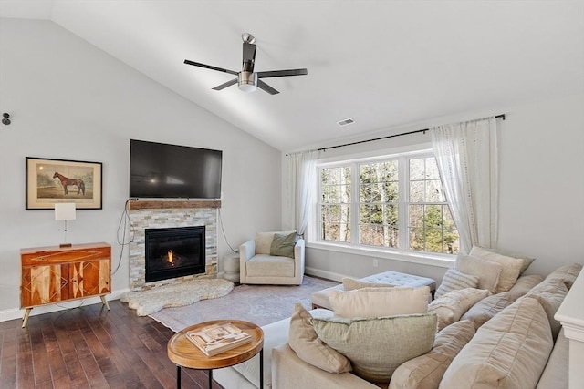 living room with visible vents, a ceiling fan, wood finished floors, vaulted ceiling, and a stone fireplace