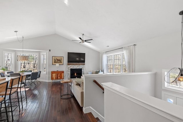 interior space featuring lofted ceiling, dark wood-style floors, a wealth of natural light, and a stone fireplace