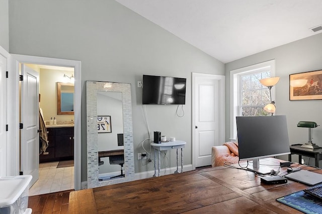 home office with lofted ceiling, hardwood / wood-style flooring, visible vents, and baseboards