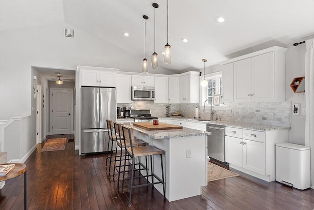 kitchen featuring a breakfast bar, a sink, white cabinetry, appliances with stainless steel finishes, and dark wood-style floors