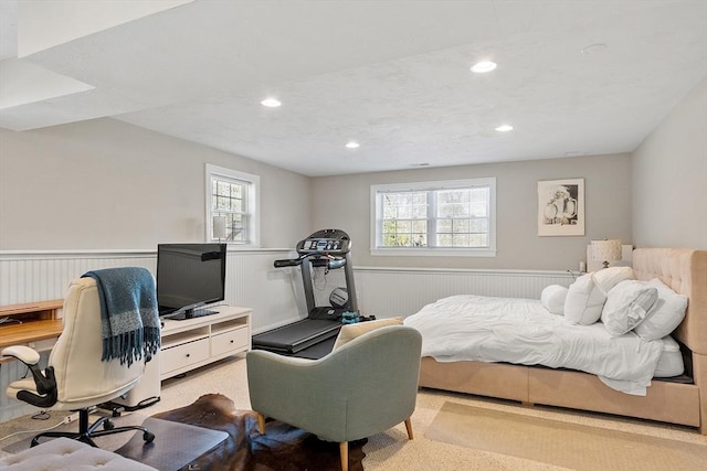 bedroom with a wainscoted wall, multiple windows, and recessed lighting