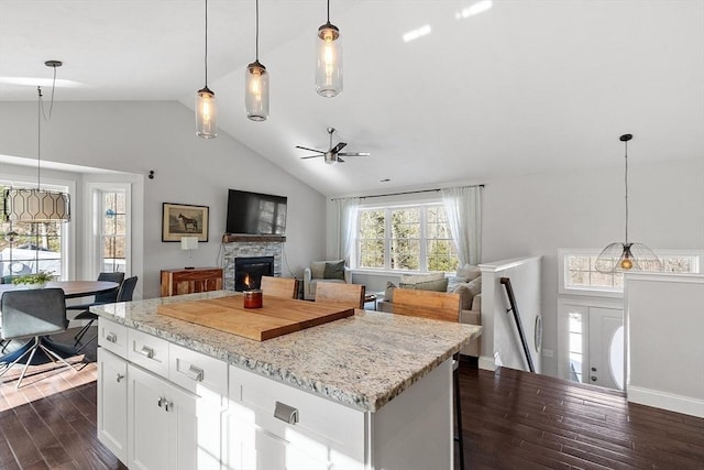 kitchen featuring dark wood-style floors, white cabinets, hanging light fixtures, and light stone countertops