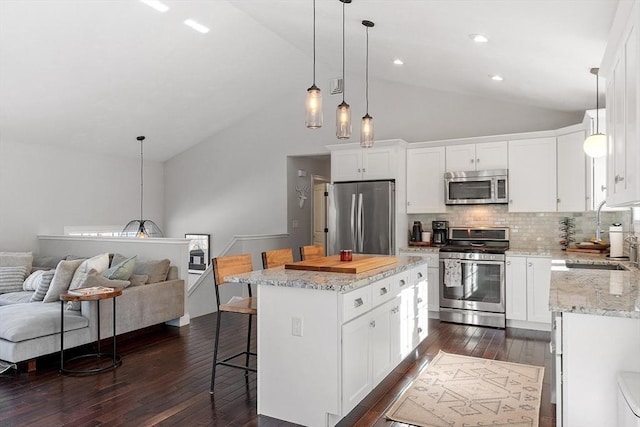 kitchen with dark wood-style floors, a breakfast bar area, appliances with stainless steel finishes, open floor plan, and a sink