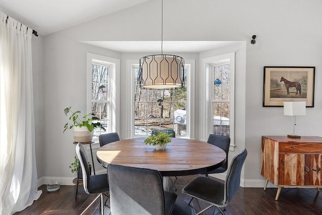 dining area featuring dark wood-style flooring, vaulted ceiling, and baseboards