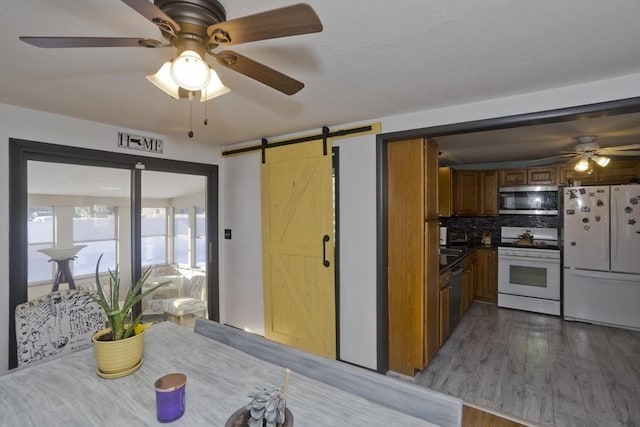 kitchen with a barn door, white appliances, brown cabinets, dark wood-style floors, and dark countertops