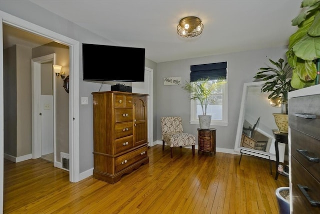 sitting room featuring light wood-style floors, visible vents, and baseboards