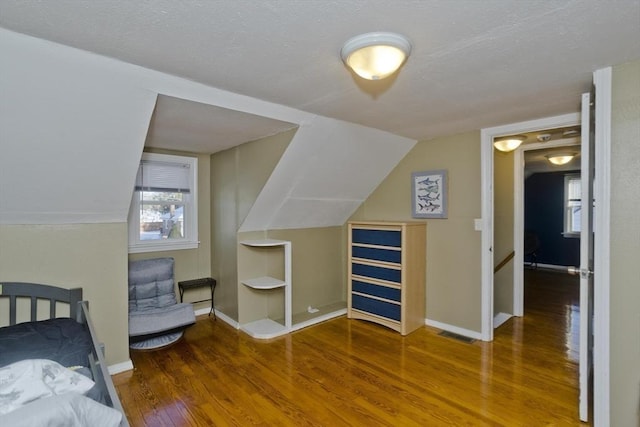 bedroom featuring lofted ceiling, visible vents, baseboards, and wood finished floors