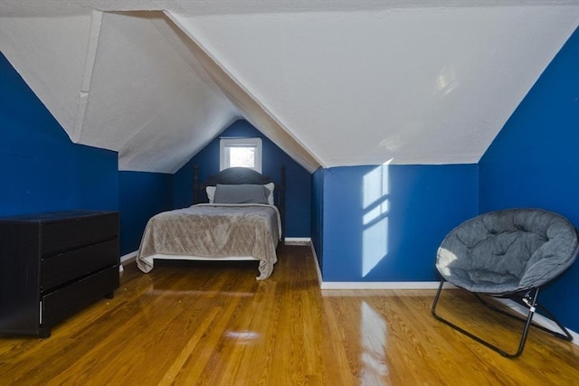 bedroom featuring baseboards, vaulted ceiling, and wood finished floors