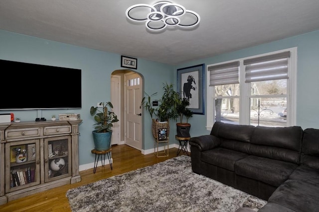 living area featuring baseboards, arched walkways, and wood finished floors