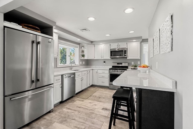 kitchen with visible vents, open shelves, a sink, light countertops, and stainless steel appliances