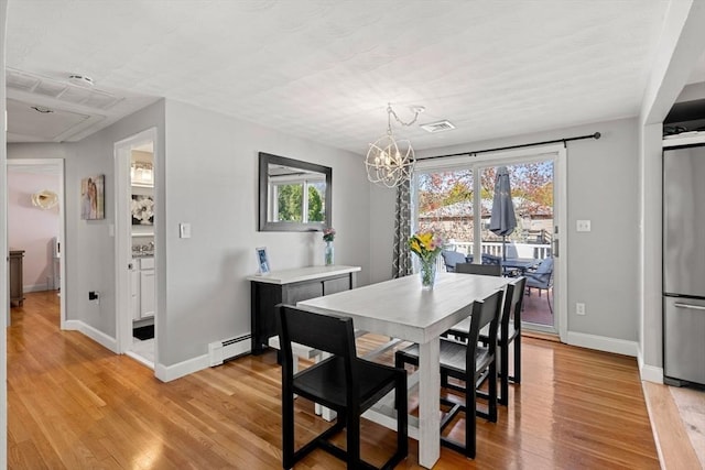 dining area with a notable chandelier, visible vents, light wood-style flooring, baseboards, and a baseboard heating unit