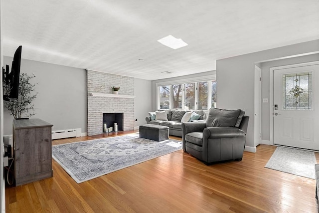 living area featuring baseboards, a baseboard radiator, wood finished floors, and a fireplace