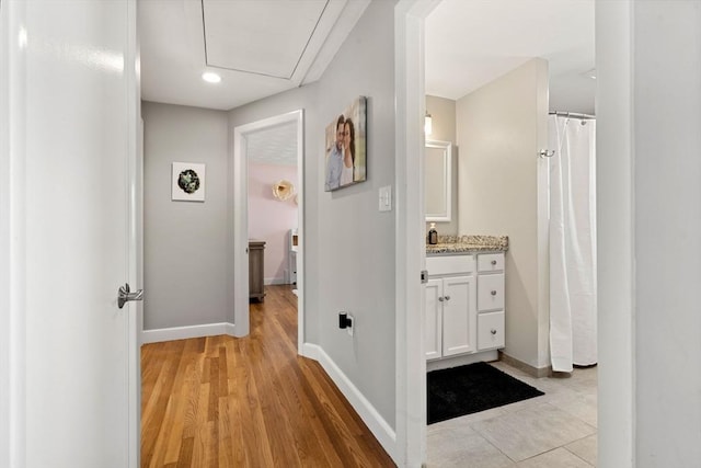 corridor featuring recessed lighting, baseboards, and light wood-type flooring