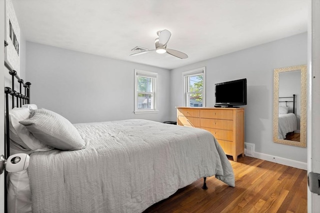 bedroom featuring baseboards, a ceiling fan, wood finished floors, and visible vents