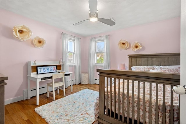 bedroom with baseboard heating, baseboards, and wood finished floors