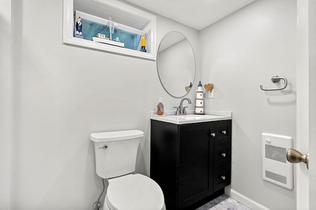 half bathroom featuring toilet, baseboards, heating unit, and vanity