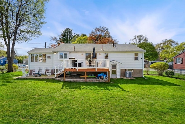 back of property featuring a lawn, a deck, cooling unit, and fence