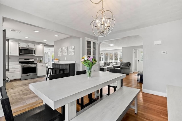 dining area with a notable chandelier, arched walkways, recessed lighting, baseboards, and visible vents