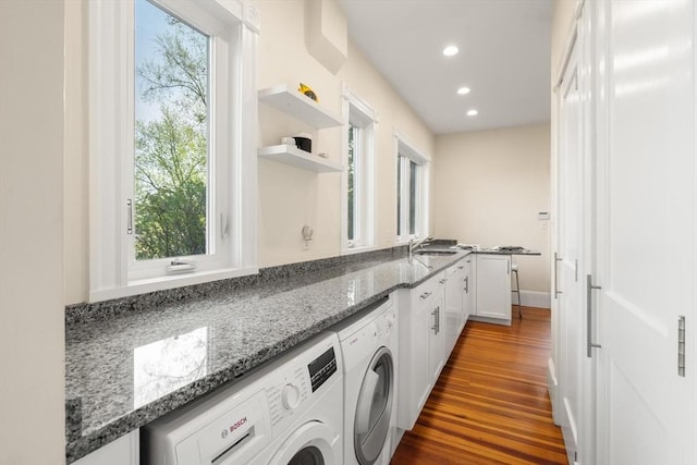 clothes washing area with washing machine and clothes dryer, dark wood-style flooring, recessed lighting, and cabinet space