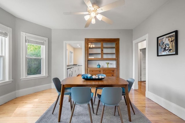 dining space with light wood finished floors, baseboards, and a ceiling fan