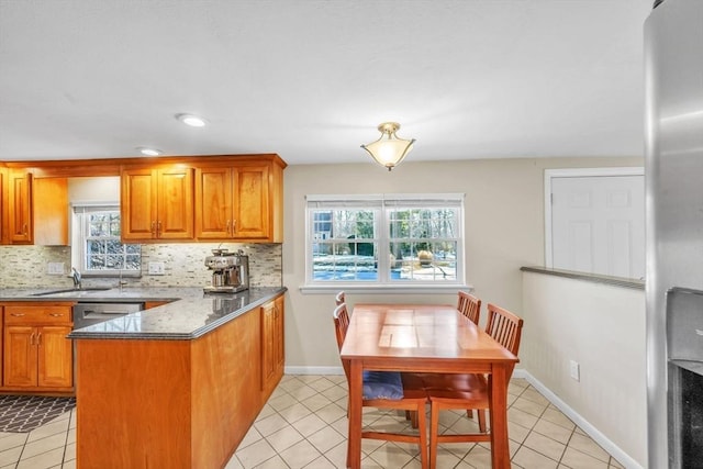 kitchen featuring light tile patterned flooring, dishwasher, sink, and dark stone countertops