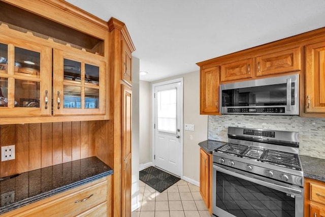 kitchen featuring light tile patterned flooring, appliances with stainless steel finishes, tasteful backsplash, and dark stone counters