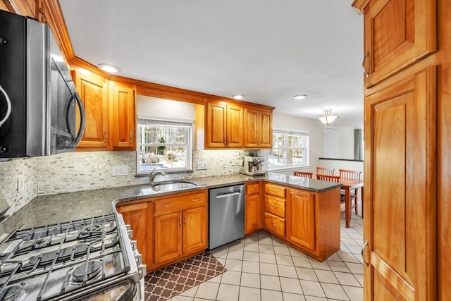 kitchen featuring appliances with stainless steel finishes, backsplash, kitchen peninsula, and sink