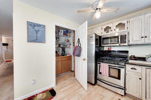 1051 Elm St Unit 8, West Springfield, MA 01089 - kitchen with appliances with stainless steel finishes, a ceiling fan, glass insert cabinets, light wood finished floors, and dark countertops