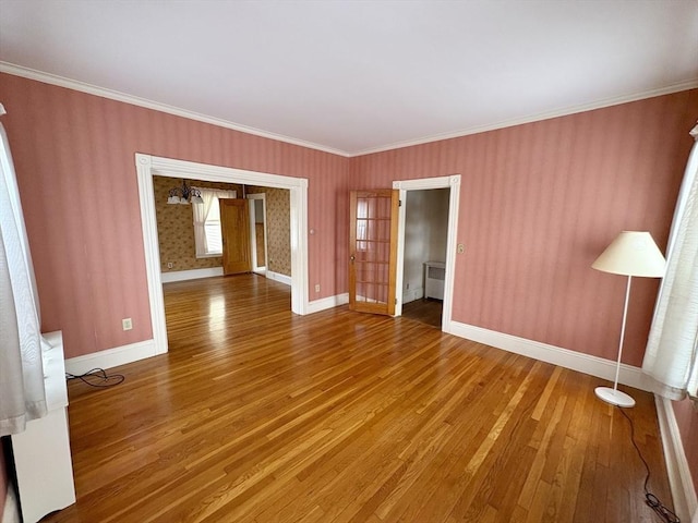 spare room with baseboards, wood finished floors, and ornamental molding