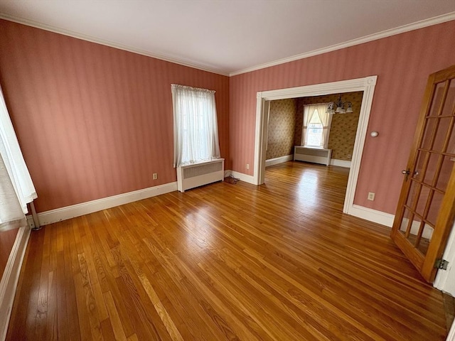 unfurnished room featuring radiator heating unit, crown molding, baseboards, and wood finished floors