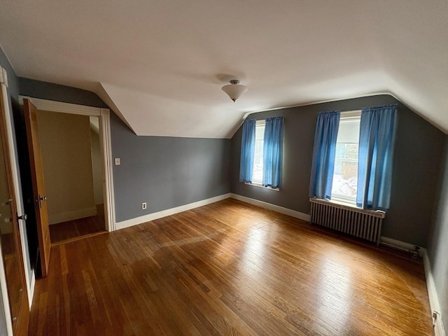 additional living space with lofted ceiling, radiator, baseboards, and wood finished floors