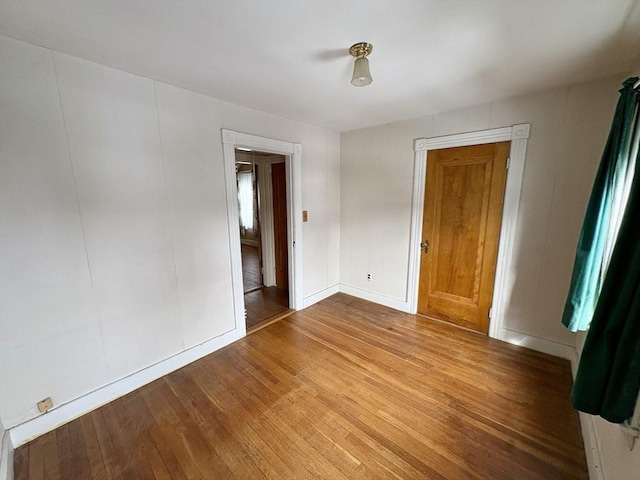 unfurnished room with hardwood / wood-style floors and baseboards