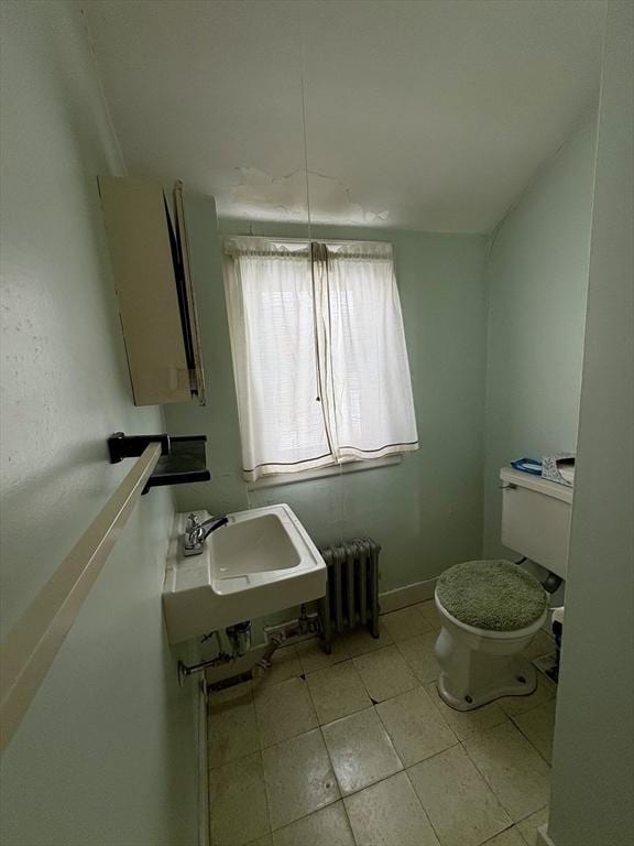 half bath featuring radiator heating unit, a sink, and toilet